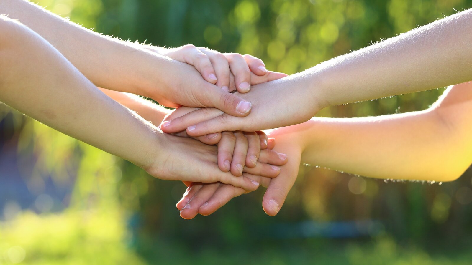 Mehrere Hände liegen übereinander als Symbol des Zusammenhalts.